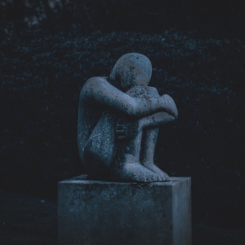 Das Bild zeigt eine kauernde Steinfigur